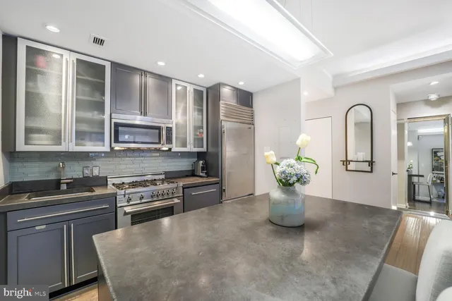 a kitchen with stainless steel appliances granite countertop a refrigerator a sink dishwasher and white cabinets with wooden floor