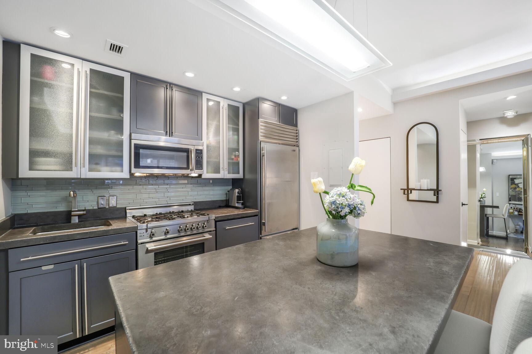 3251 Prospect Street Northwest, Unit 410 Washington, DC 20007 - Photo 8 of 16 a kitchen with stainless steel appliances granite countertop a refrigerator a sink dishwasher and white cabinets with wooden floor