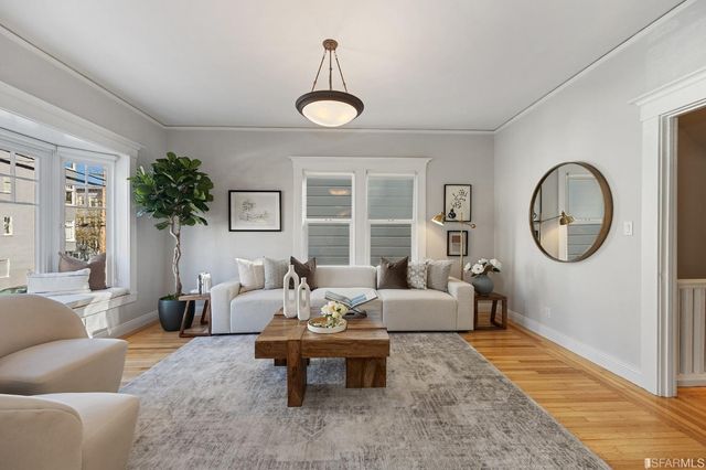 a living room with furniture a rug potted plant and a large window