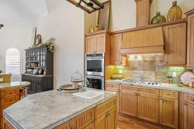 a kitchen with stainless steel appliances kitchen island granite countertop a sink stove and cabinets