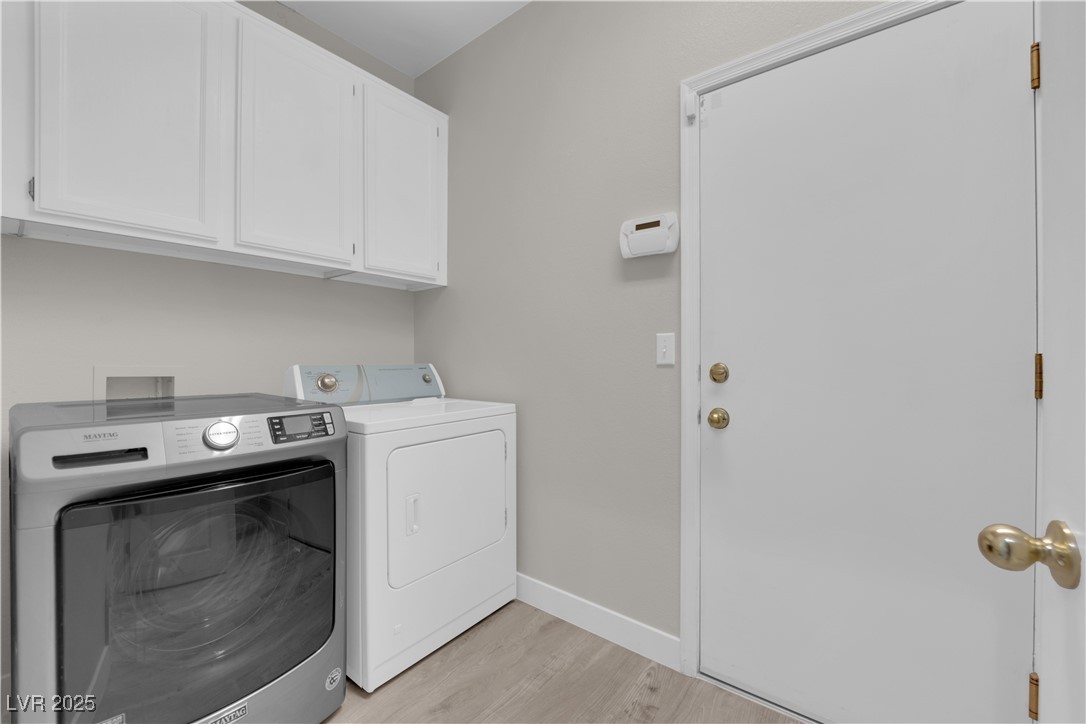 650 West Victory Road Henderson, NV 89015 - Photo 17 of 35 Laundry area featuring cabinet space, light wood-style flooring, and washing machine and clothes dryer