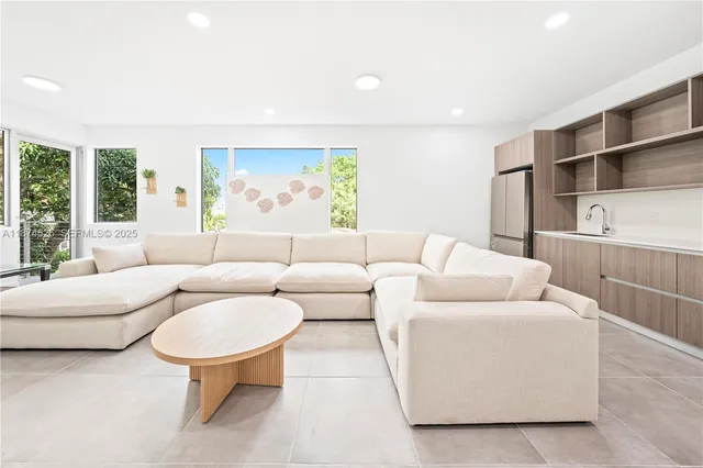 a living room with stainless steel appliances furniture and a kitchen view
