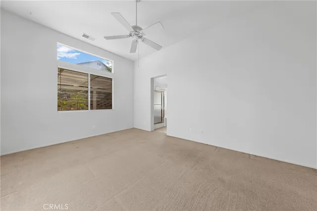 en empty room with windows and chandelier fan
