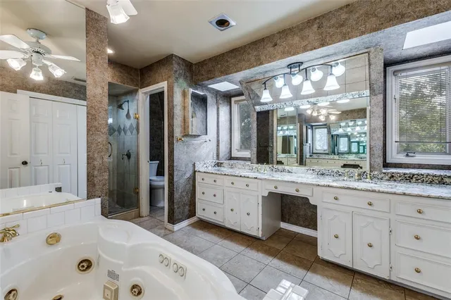 a bathroom with a granite countertop double vanity sink a large mirror and a bathtub