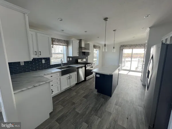 a kitchen with stainless steel appliances kitchen island granite countertop wooden floors wooden cabinets a sink and a window