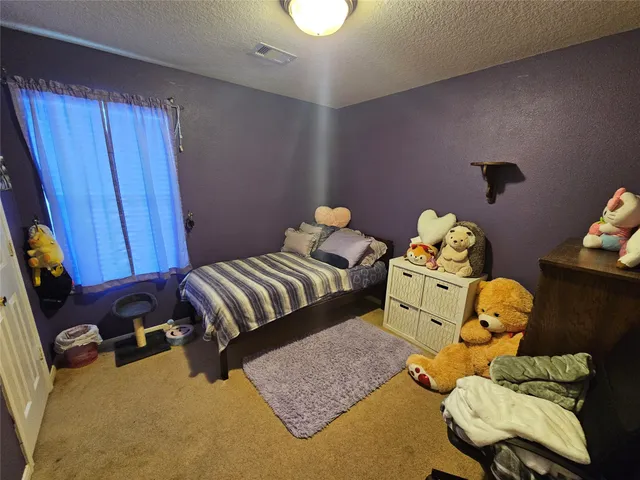 a bedroom with a bed and teddy bear on bed