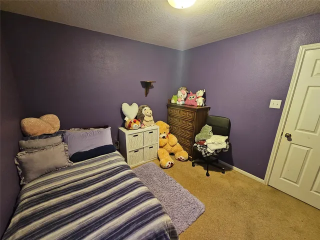 a bedroom with a bed and teddy bear on bed