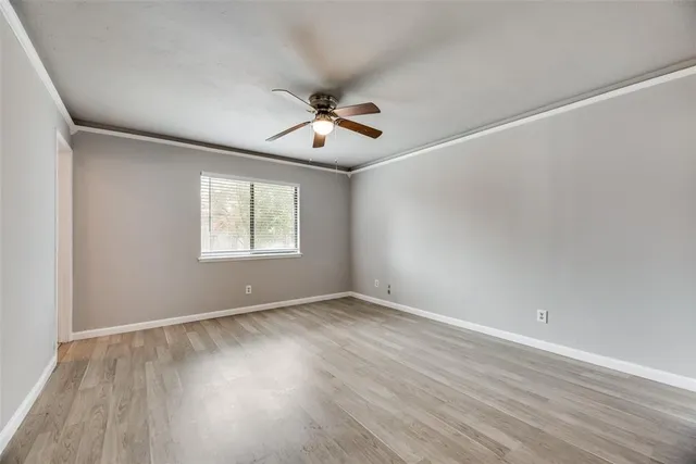 an empty room with wooden floor ceiling fan and windows