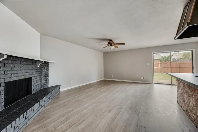 an empty room with wooden floor fireplace and windows