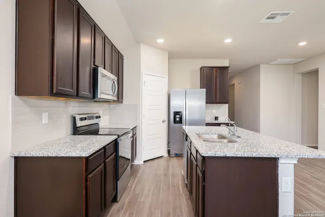 a kitchen with stainless steel appliances granite countertop a sink stove refrigerator and cabinets
