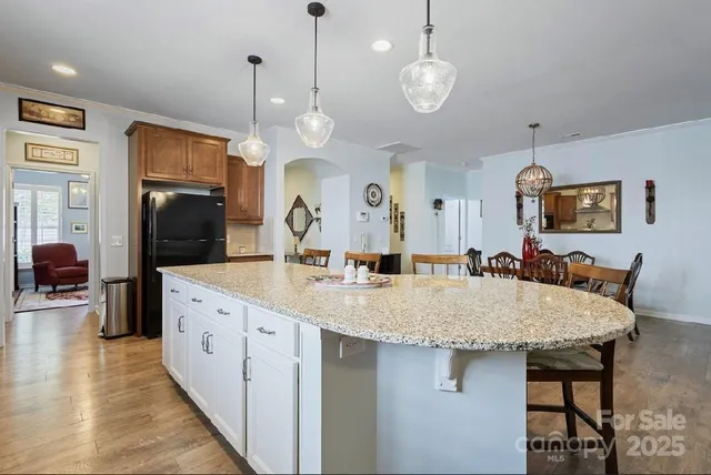 a large kitchen with granite countertop a island a sink stainless steel appliances and furniture