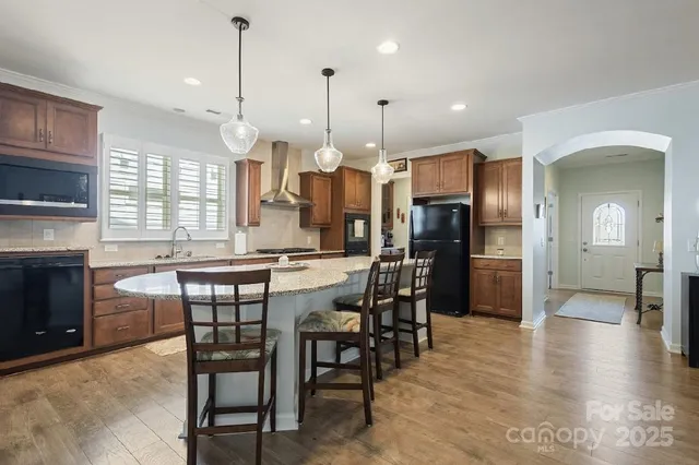 a kitchen with stainless steel appliances kitchen island granite countertop a table chairs sink and window