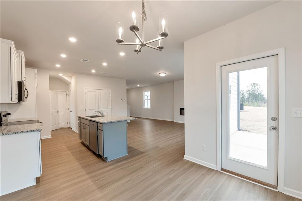 106 Windmill Court Calhoun, GA 30701 - Photo 10 of 29 a open kitchen with kitchen island a sink dishwasher stove and white cabinets with wooden floor next to windows