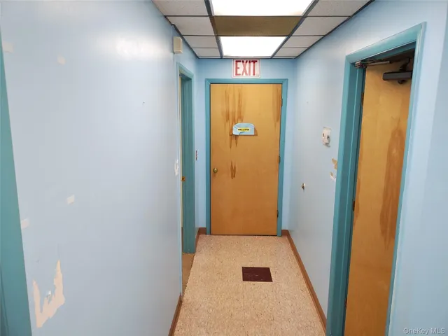 a view of a hallway with wooden floor and a refrigerator