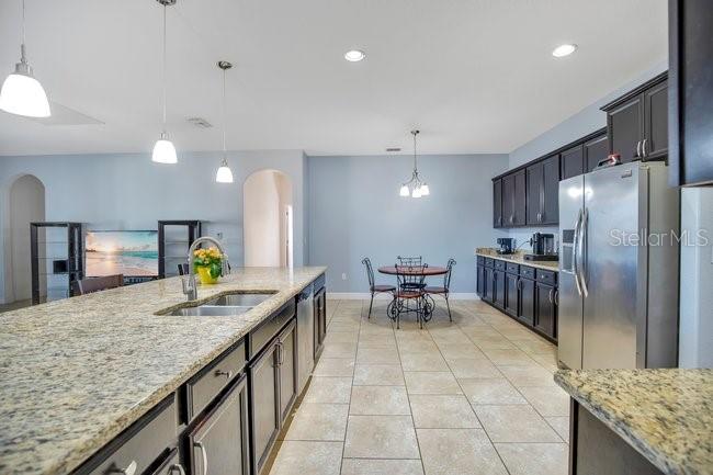 1422 Sharon Rose Trace Deltona, FL 32725 - Photo 23 of 42 a kitchen with stainless steel appliances granite countertop table chairs and refrigerator