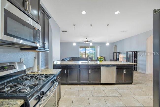 1422 Sharon Rose Trace Deltona, FL 32725 - Photo 24 of 42 a kitchen with stainless steel appliances granite countertop a stove a sink dishwasher and a refrigerator