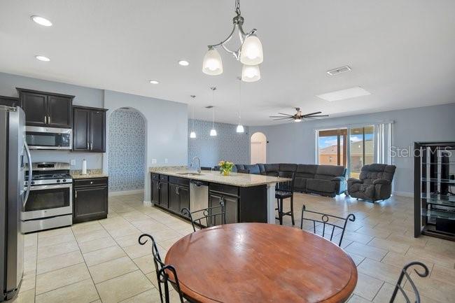 1422 Sharon Rose Trace Deltona, FL 32725 - Photo 25 of 42 a kitchen with stainless steel appliances kitchen island granite countertop a stove a refrigerator a sink a dining table and chairs with wooden floor