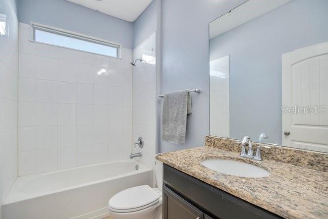 1422 Sharon Rose Trace Deltona, FL 32725 - Photo 32 of 42 a bathroom with a granite countertop tub sink toilet and mirror