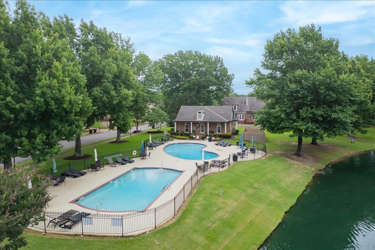 1876 Liles Lane Collierville, TN 38017 - Photo 29 of 36 Two fenced swimming pools with surrounding lounge areas, bordered by a green lawn and mature trees