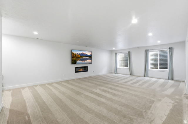 108 West Monte Rosa Lane Midway, UT 84049 - Photo 34 of 48 Spacious room featuring light-toned carpeting with subtle stripes, recessed lighting, and a wall-mounted linear fireplace