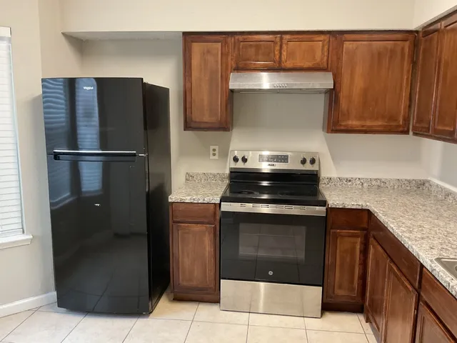 a kitchen with stainless steel appliances granite countertop a refrigerator and a stove