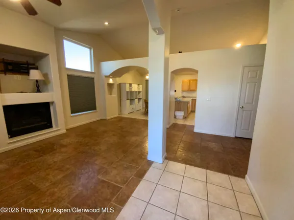 a view of a hallway to an empty room with a fireplace and cabinet