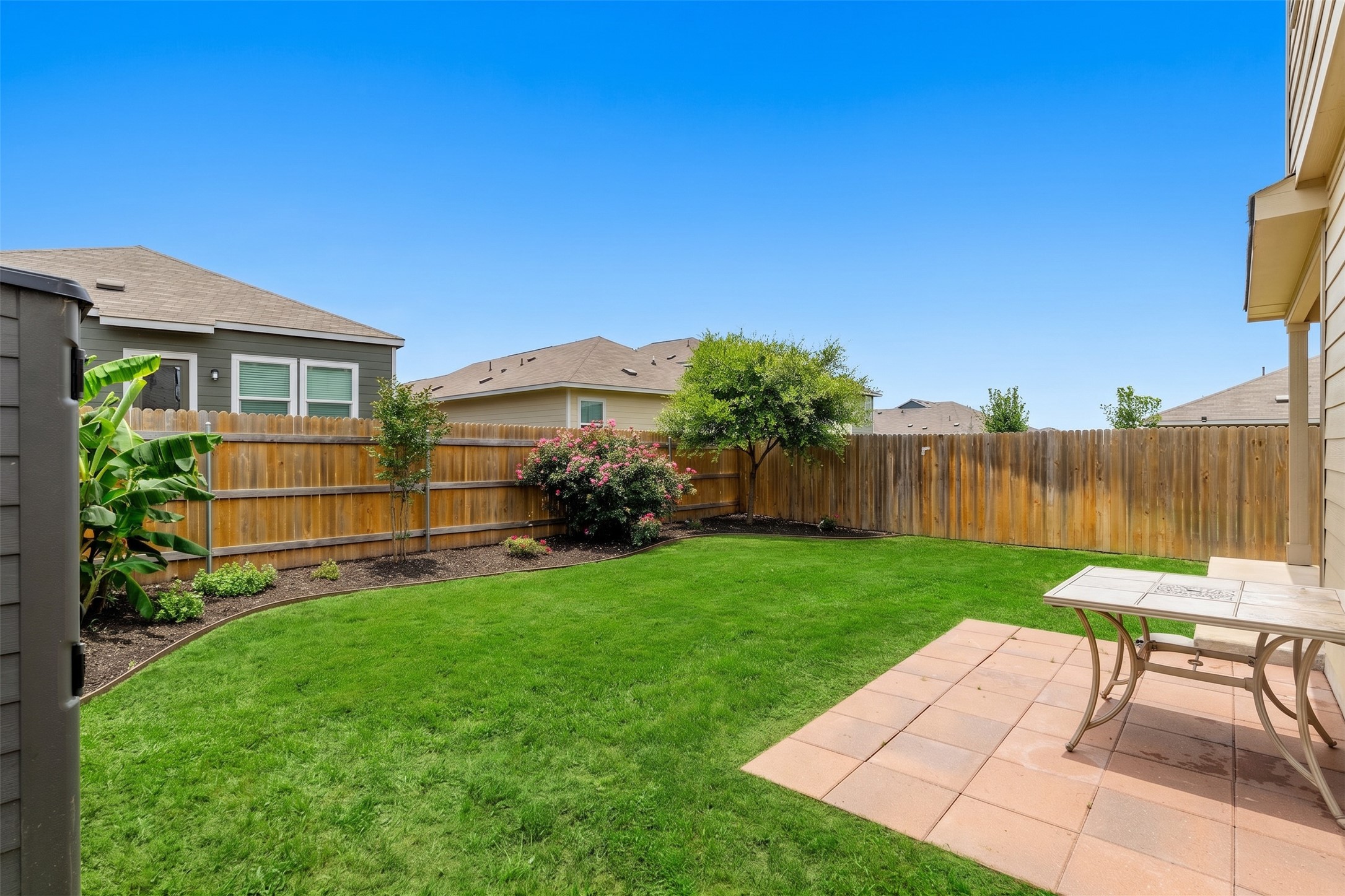 425 Perfect World Loop Jarrell, TX 76537 - Photo 26 of 29 Expansive backyard featuring a lush lawn, a privacy fence, and a paver patio