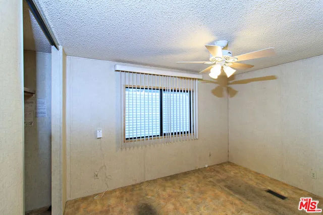 an empty room with a chandelier fan and windows