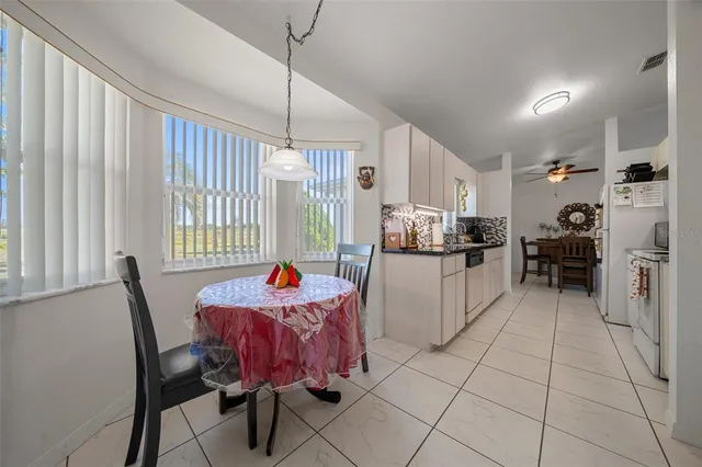 a kitchen with stainless steel appliances kitchen island granite countertop dining table chairs and a refrigerator
