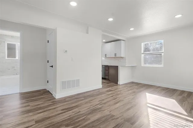 an empty room with wooden floor cabinet and windows