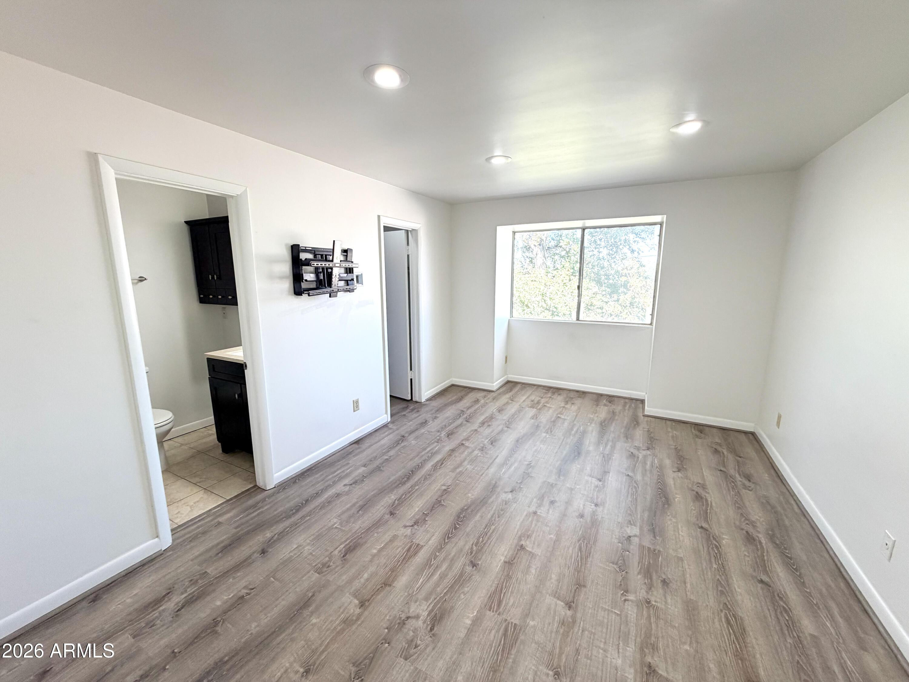 1016 East Osborn Road, Unit F Phoenix, AZ 85014 - Photo 7 of 14 an empty room with wooden floor and windows