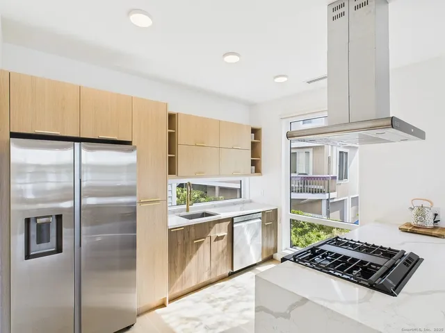 a kitchen with stainless steel appliances granite countertop a refrigerator a sink and a stove