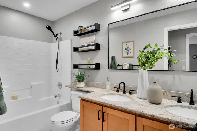 a bathroom with a granite countertop sink a toilet and shower