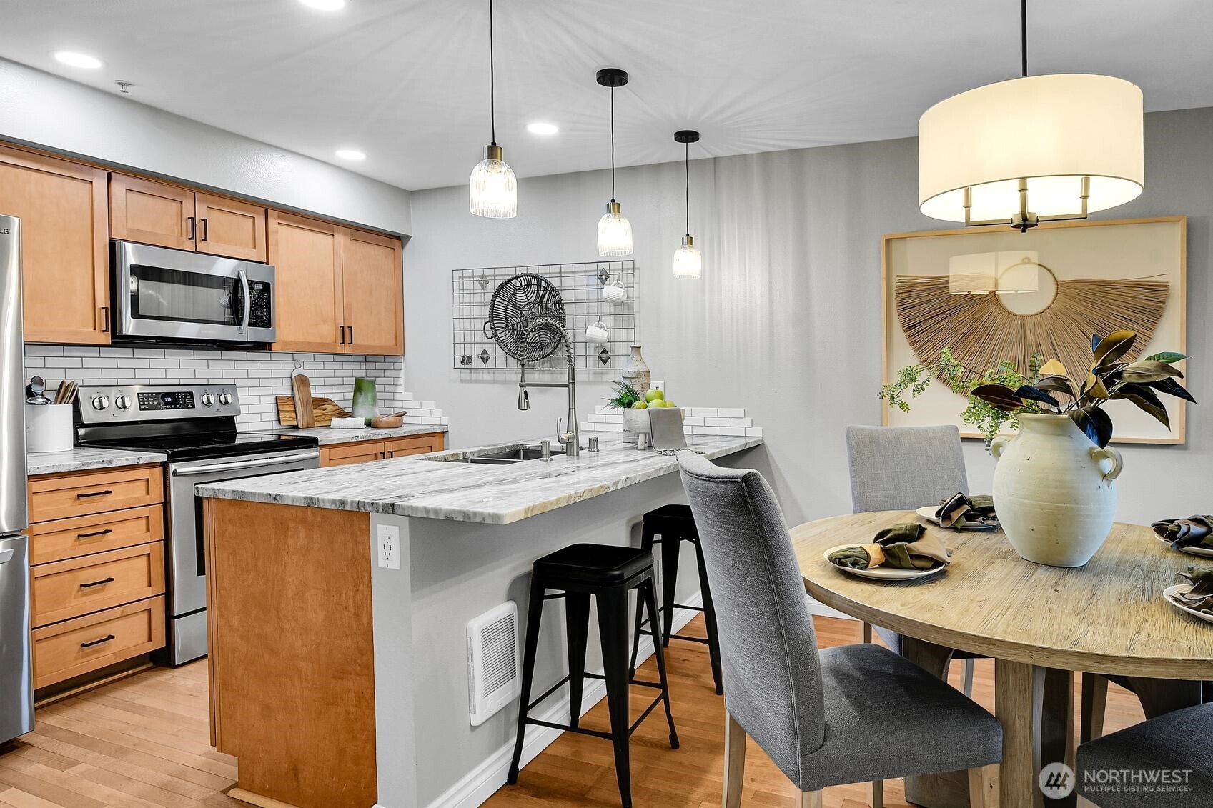 18930 Bothell Everett Highway, Unit F305 Bothell, WA 98012 - Photo 5 of 20 a kitchen with stainless steel appliances granite countertop a kitchen island a stove a sink a dining table and chairs with wooden floor