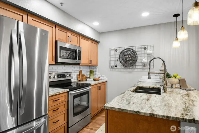 a kitchen with stainless steel appliances granite countertop a stove a sink and a refrigerator