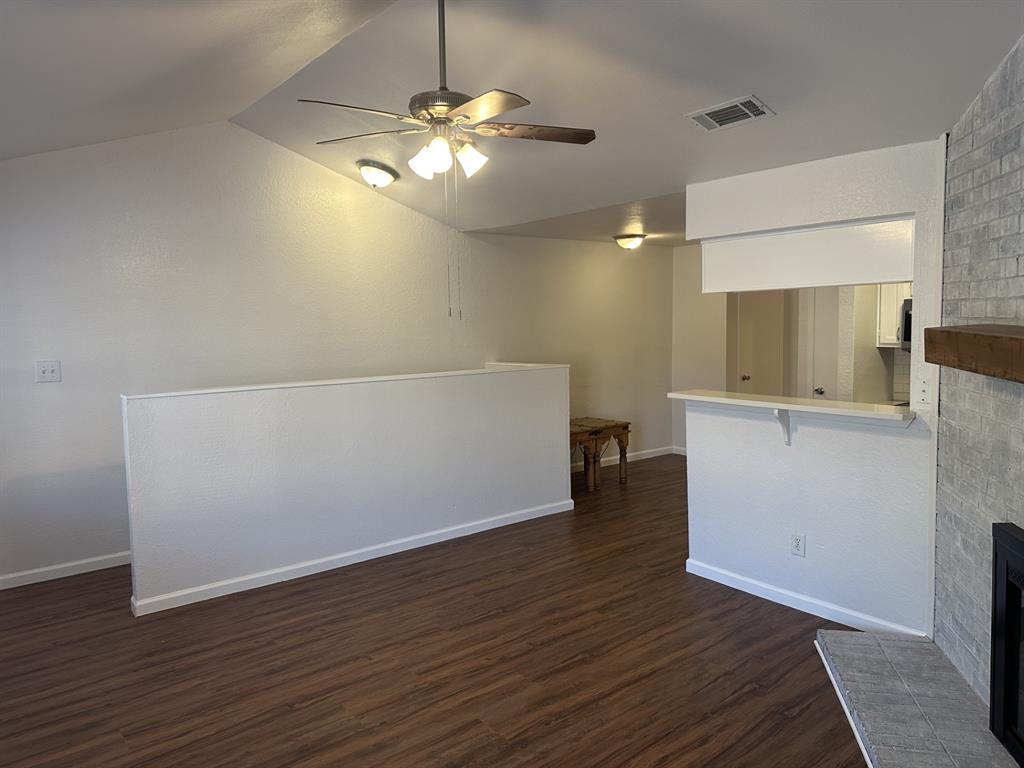 2400 Jupiter Road, Unit D2 Plano, TX 75074 - Photo 5 of 17 Unfurnished living room with ceiling fan, dark wood-type flooring, a fireplace, and vaulted ceiling