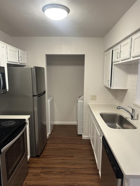 2400 Jupiter Road, Unit D2 Plano, TX 75074 - Photo 7 of 17 Kitchen featuring white cabinets, appliances with stainless steel finishes, dark wood-style floors, separate washer and dryer, and a textured ceiling