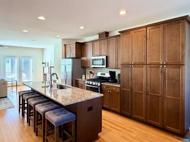 a kitchen with granite countertop stainless steel appliances a refrigerator a stove a dining table and chairs