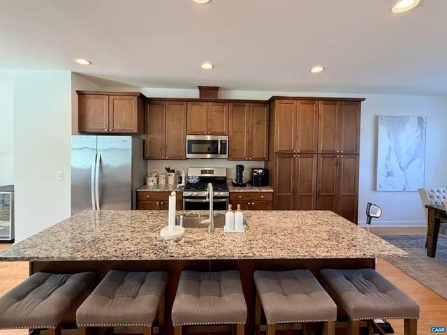 a kitchen with kitchen island a dining table chairs and refrigerator