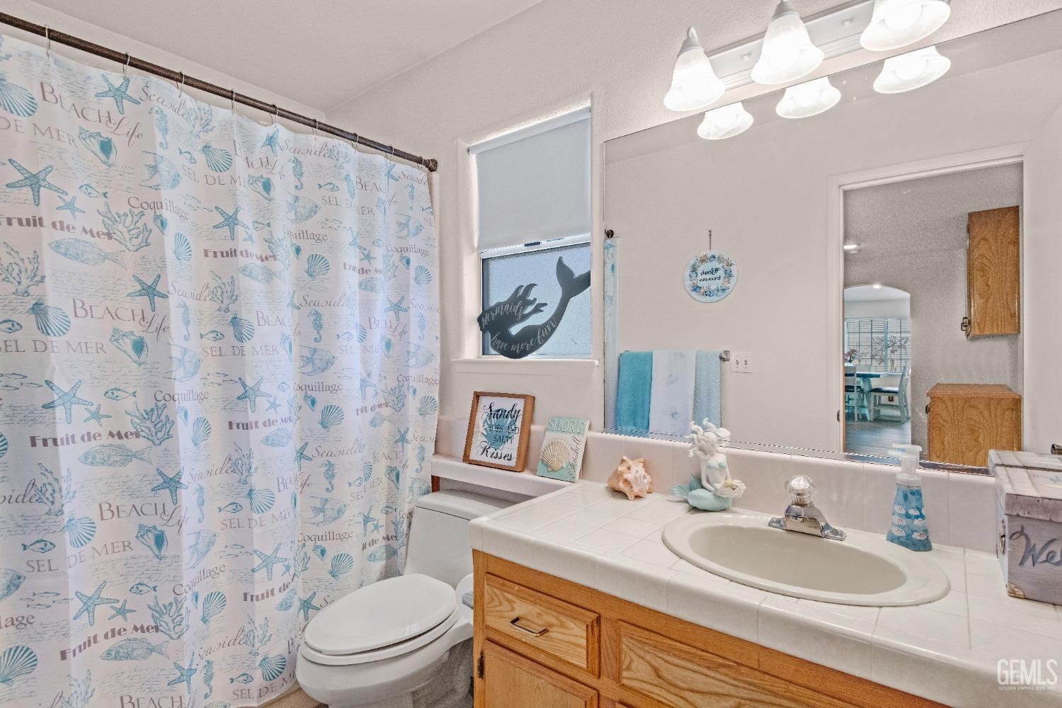 Undisclosed Address Bakersfield, CA 93312 - Photo 27 of 43 a bathroom with a granite countertop toilet a sink a mirror and a shower