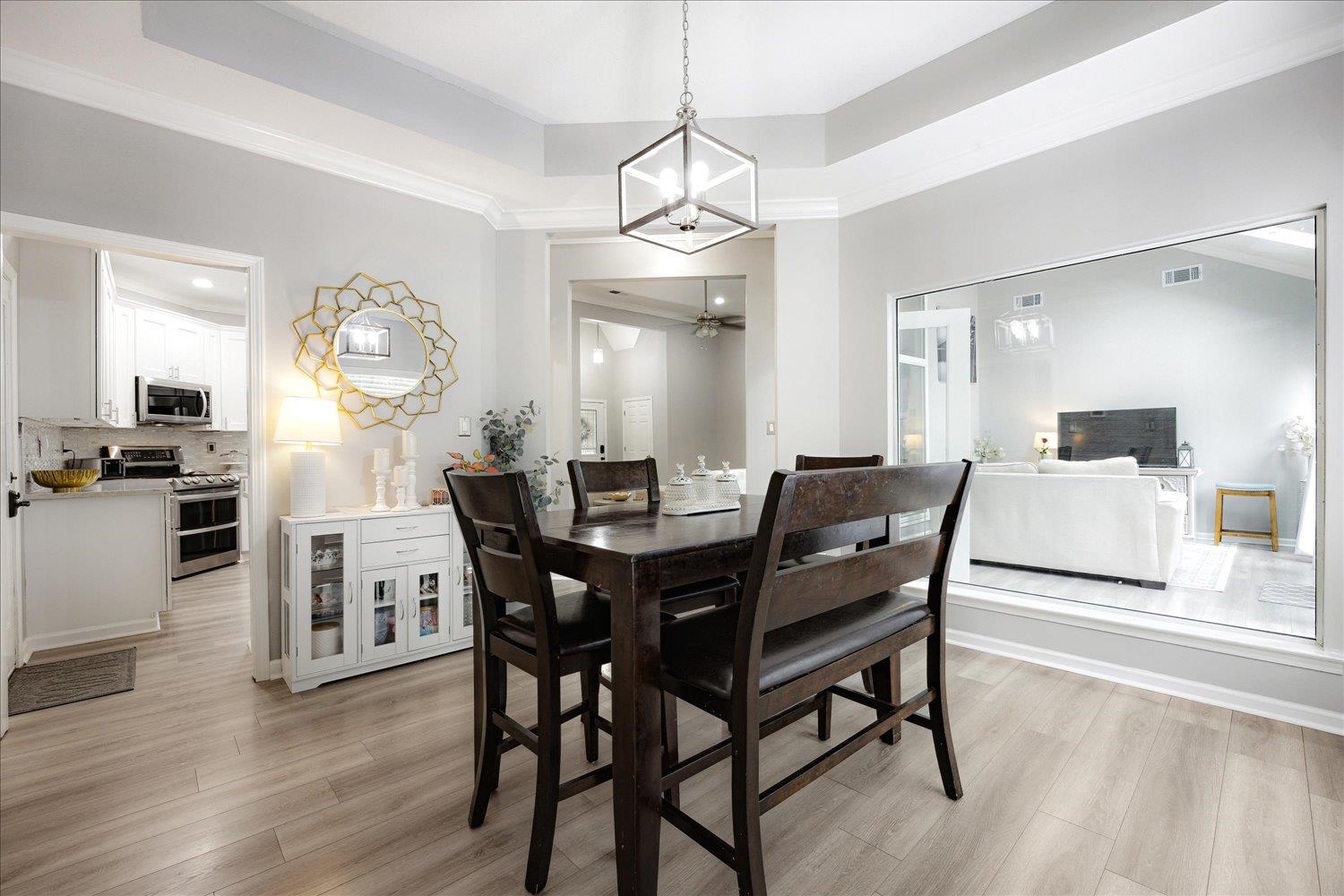 5950 Benjestown Road Memphis, TN 38127 - Photo 8 of 25 Dining area with a chandelier, light wood finished floors, a tray ceiling, and crown molding