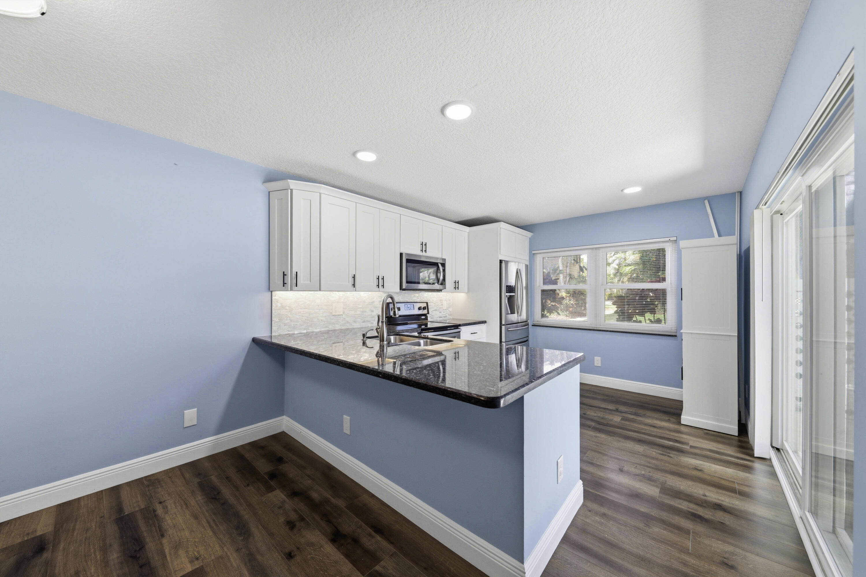 4802 Roxbury Court Boynton Beach, FL 33436 - Photo 9 of 41 a kitchen with stainless steel appliances granite countertop a sink cabinets and wooden floor