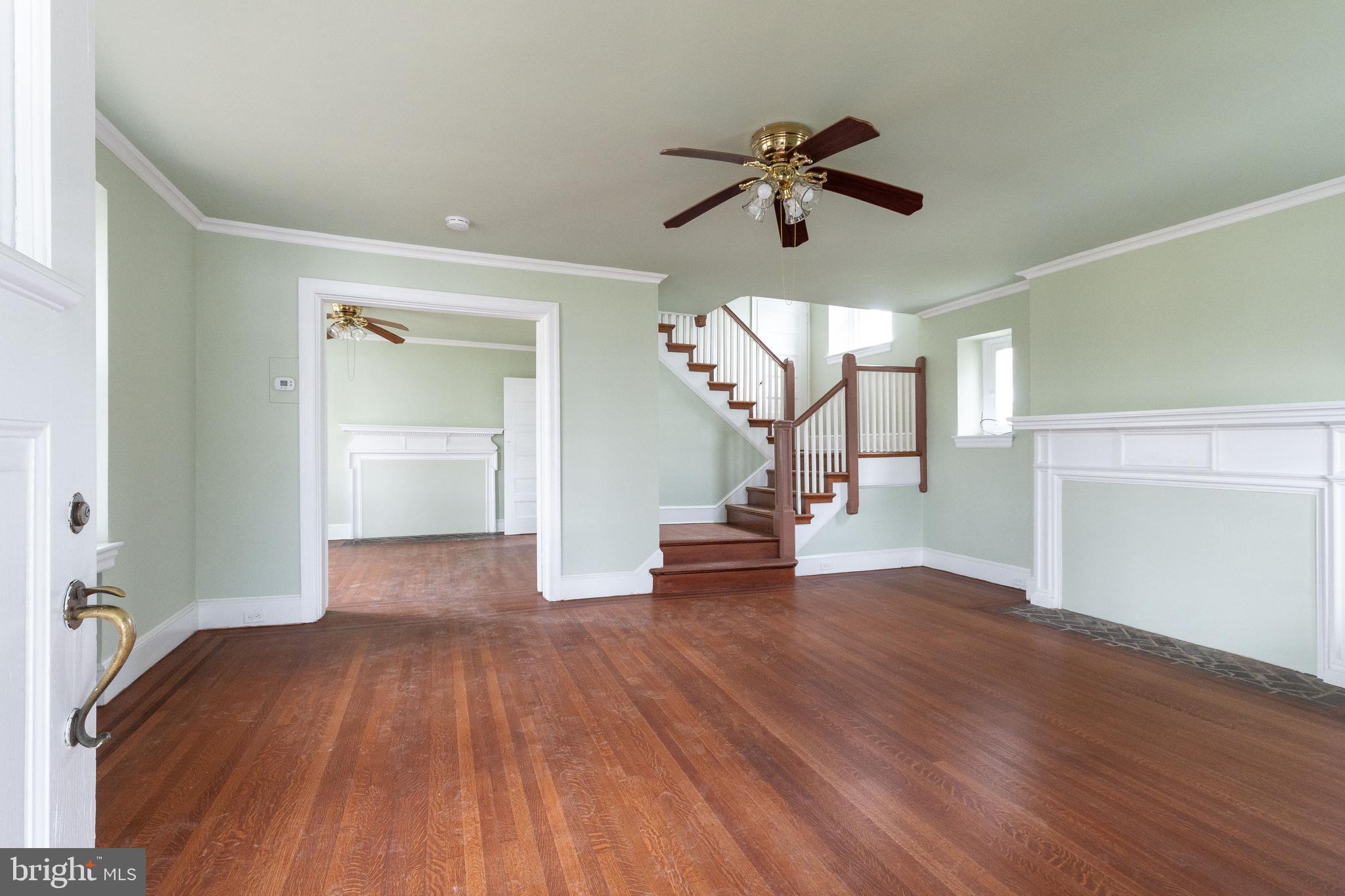 a view of empty room with wooden floor and fan