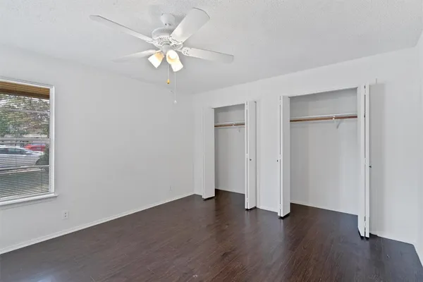 an empty room with wooden floor and ceiling fan