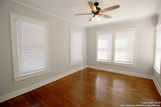 a view of an empty room with window and a chandelier fan