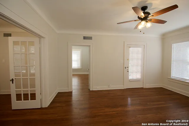 a view of an empty room with window and wooden floor