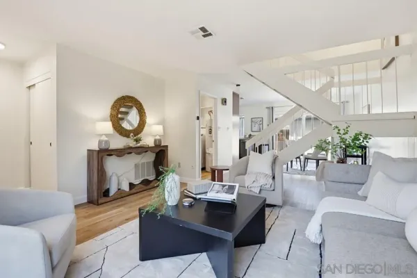 a living room with furniture a clock and a view of kitchen