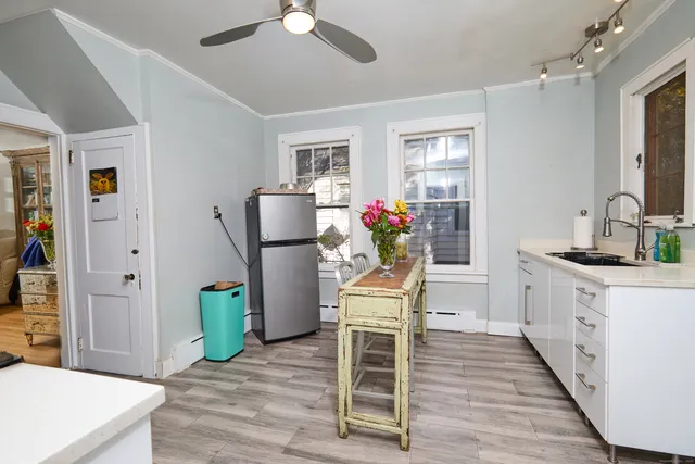 a living room with furniture a refrigerator and a wooden floor