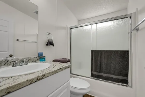 a bathroom with a granite countertop sink a toilet and shower