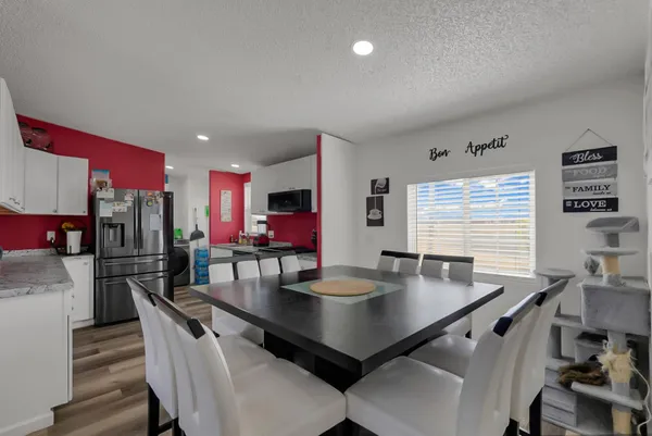 a room with stainless steel appliances a table chairs and a wooden floor